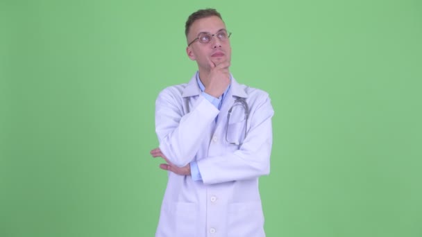 Feliz homem bonito médico pensando e olhando para cima — Vídeo de Stock