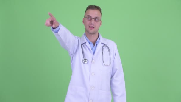 Happy handsome man doctor pointing finger — Stock Video