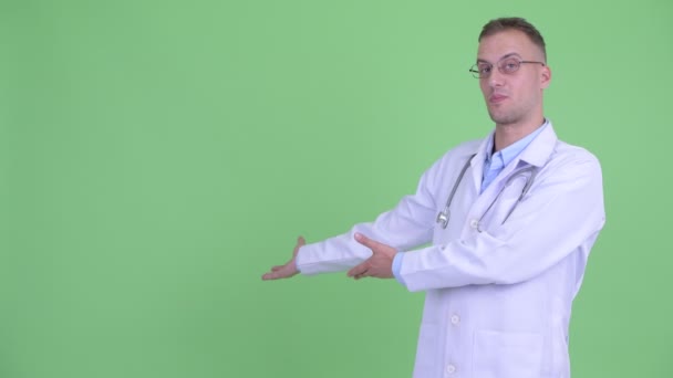 Щасливий красивий чоловік лікар розмовляє, показуючи на спину — стокове відео