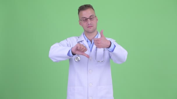 Confused man doctor choosing between thumbs up and thumbs down — Stock Video