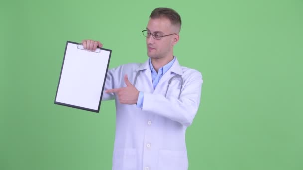 Счастливый красавчик доктор показывает планшет и показывает большие пальцы — стоковое видео
