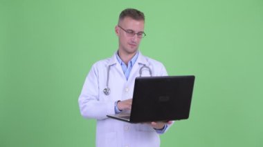Mutlu yakışıklı adam doktor düşünme dizüstü bilgisayar kullanırken