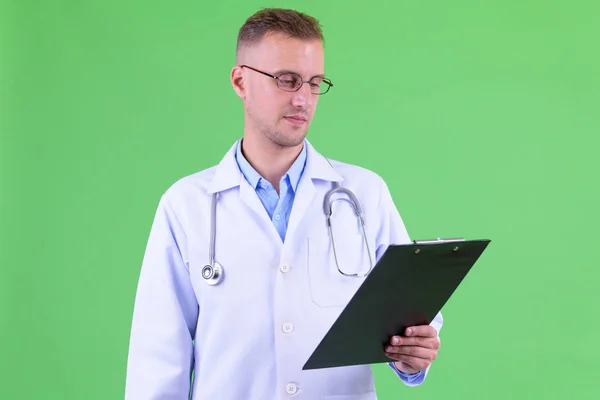 Bonito médico homem com óculos lendo na área de transferência — Fotografia de Stock