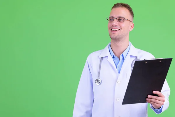Lycklig stilig man Doctor tänkande medan du håller Urklipp — Stockfoto