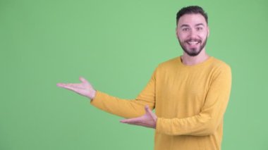 Mutlu genç yakışıklı sakallı adam bir şey gösteren ve şaşırmış görünümlü