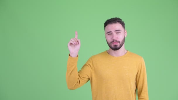 Happy young handsome bearded man talking and pointing up — Stock Video