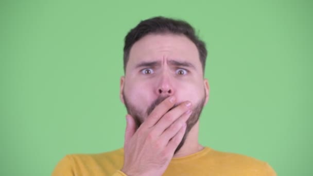 Лицо молодого красивого бородатого мужчину, выглядящего шокированным — стоковое видео