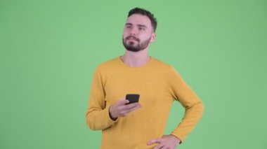 Mutlu genç yakışıklı sakallı adam telefon kullanırken düşünme