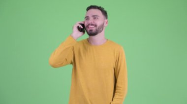 Mutlu genç yakışıklı sakallı adam telefonda konuşuyor