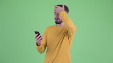 Stresli genç sakallı adam telefon kullanarak ve kötü haber alıyorum