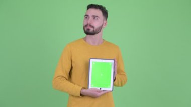 Mutlu genç yakışıklı sakallı adam dijital tablet gösterirken düşünme