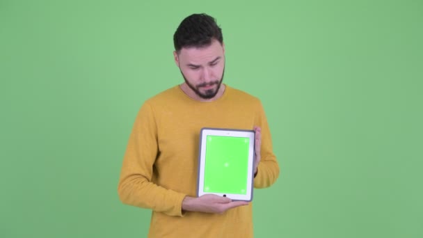 Hombre barbudo joven estresado mostrando tableta digital — Vídeos de Stock
