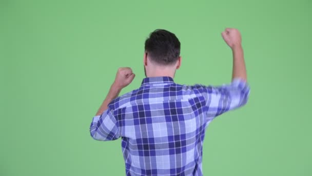 Вид ззаду щасливого молодого бородатого хіпстера з піднятими кулаками — стокове відео
