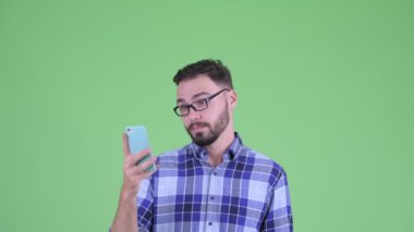 Telefon kullanarak ve şok görünümlü genç yakışıklı sakallı hipster adam Yüzü