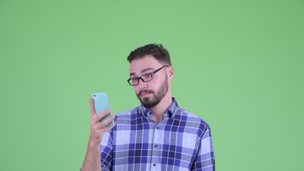 Cara de joven guapo barbudo hipster hombre usando el teléfono y mirando sorprendido — Vídeos de Stock