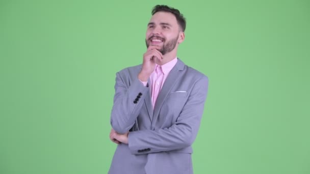Счастливый молодой бородатый бизнесмен думает и смотрит вверх — стоковое видео