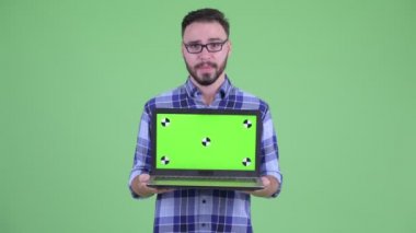 Stresli genç sakallı hipster adam dizüstü gösteren
