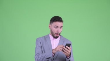 Mutlu genç sakallı işadamının yüzü telefon kullanıyor ve şaşırmış görünüyor