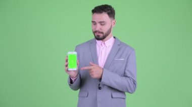 Mutlu genç sakallı işadamı telefon gösteren ve başparmak veren