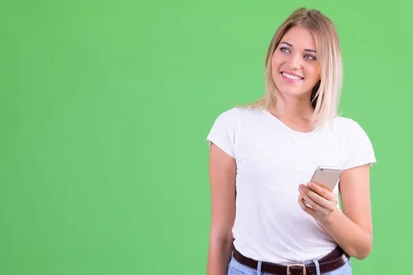 Szczęśliwy młody piękny blond kobieta myślenia podczas korzystania z telefonu — Zdjęcie stockowe