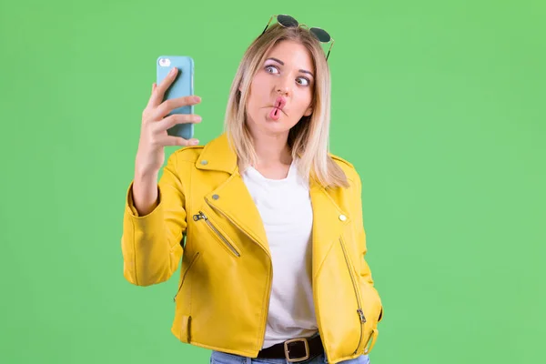 Młoda zbuntowna blondynka robi śmieszną twarz i bierze selfie — Zdjęcie stockowe