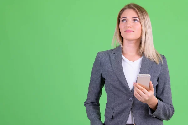 Young beautiful blonde businesswoman thinking while using phone — Stock Photo, Image