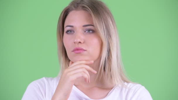 Gezicht van beklemtoonde jonge blonde vrouw die denkt en naar beneden kijkt — Stockvideo