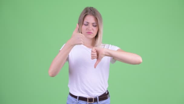 Mylić młody blond kobieta wybór między kciuki w górę i kciuki w dół — Wideo stockowe