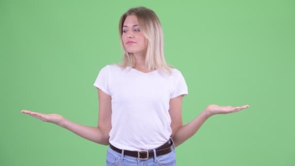 Glückliche junge schöne blonde Frau, die etwas vergleicht — Stockvideo
