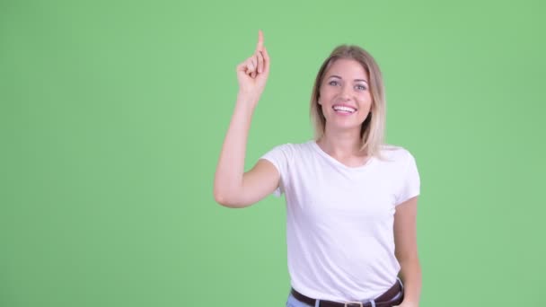 Happy young beautiful blonde woman talking while pointing up — Stock Video