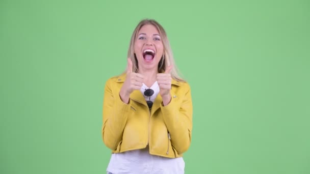 Glückliche junge rebellische blonde Frau gibt die Daumen nach oben und sieht aufgeregt aus — Stockvideo