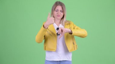Şaşkın genç asi sarışın kadın başparmak yukarı ve başparmak aşağı arasında seçim