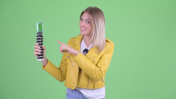 Mutlu genç asi sarışın kadın vlogging ve telefon gösteren — Stok video