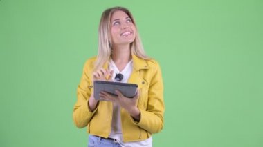 Mutlu genç asi sarışın kadın dijital tablet kullanırken düşünme