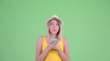 Mutlu genç sarışın turist kadın telefon kullanarak ve şaşırmış görünümlü
