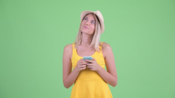 Счастливая молодая блондинка туристка думает, используя телефон — стоковое видео