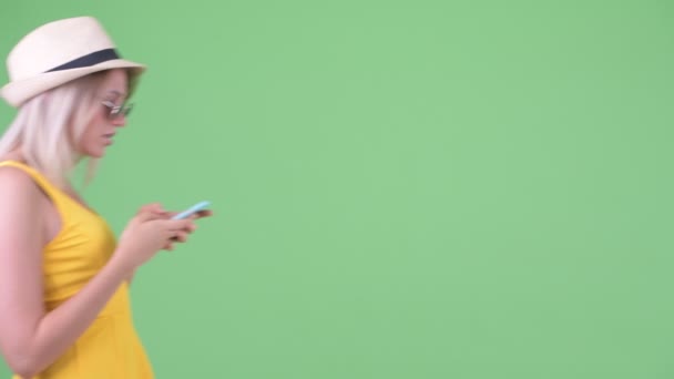 젊은 금발의 관광 여자 를 사용하여 전화 동안 찾고 위에 선글라스 — 비디오