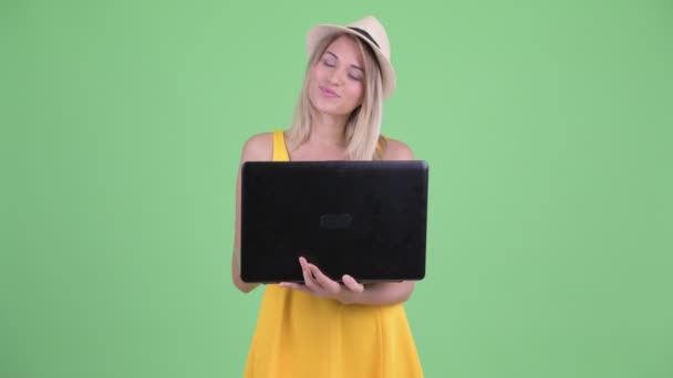 Happy young blonde tourist woman thinking while using laptop — Stock Video