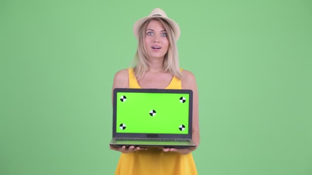 Happy young blonde tourist woman showing laptop and looking surprised — Stock Video