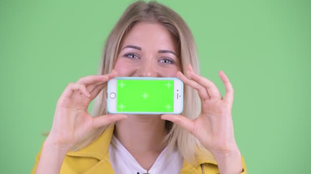 Gezicht van gelukkige jonge rebelse blonde vrouw toont telefoon — Stockvideo