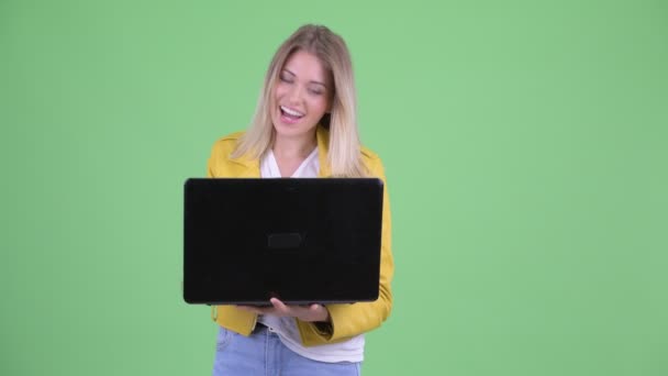 Ευτυχισμένος νέος επαναστάτρια ξανθιά γυναίκα μιλάει ενώ χρησιμοποιεί το laptop — Αρχείο Βίντεο