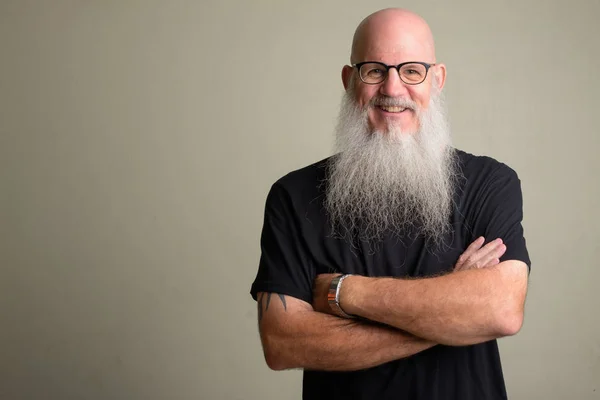 Happy mature bearded bald man wearing eyeglasses with arms crossed