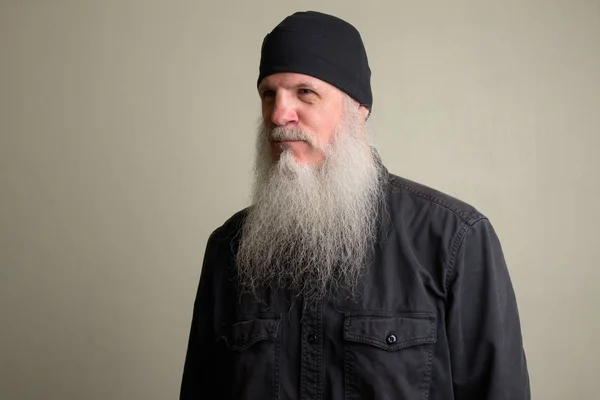 Зрелый мужчина с длинной седой бородой думает и носит шапочку — стоковое фото