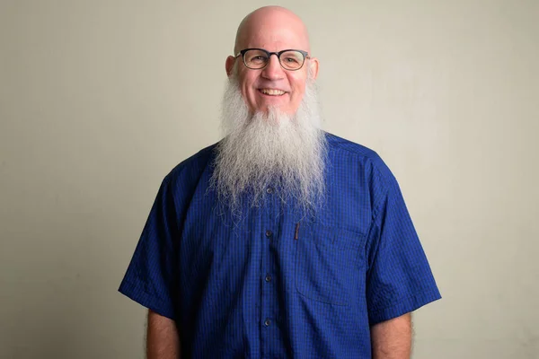 Happy mature bald man with long gray beard smiling and wearing eyeglasses