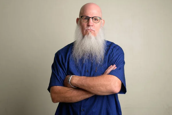 Angry mature bearded bald man wearing eyeglasses with arms crossed