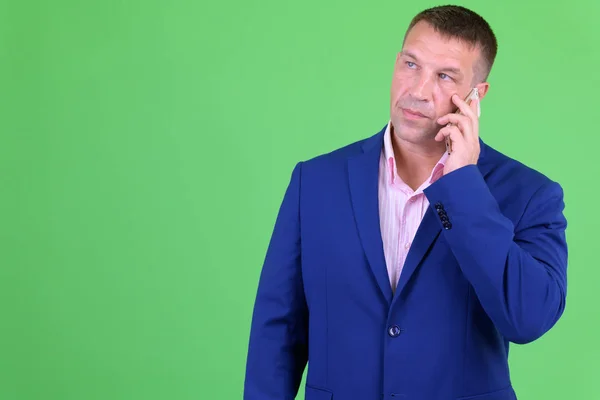 Reifer Macho-Geschäftsmann im Anzug denkt beim Telefonieren — Stockfoto