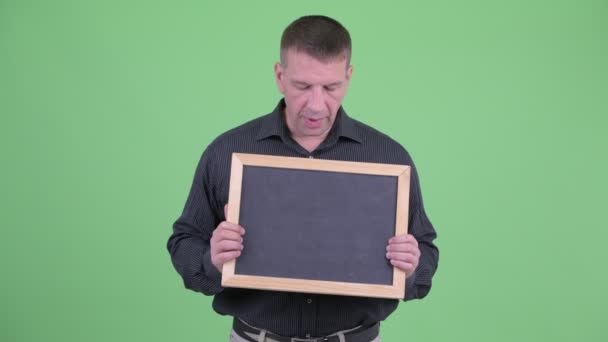 Macho volwassen zakenman praten terwijl het houden van Blackboard — Stockvideo