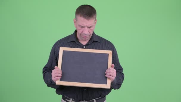 Angry macho volwassen zakenman Holding Blackboard — Stockvideo