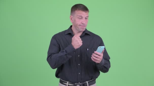 Щасливий мачо зрілий бізнесмен використовує телефон і отримує хороші новини — стокове відео