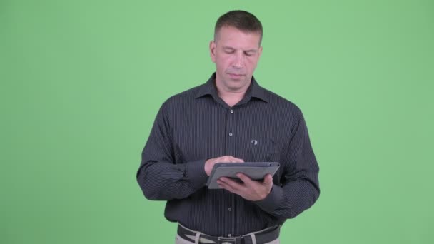 デジタルタブレットを使いながら考えるマチョ成熟したビジネスマン — ストック動画